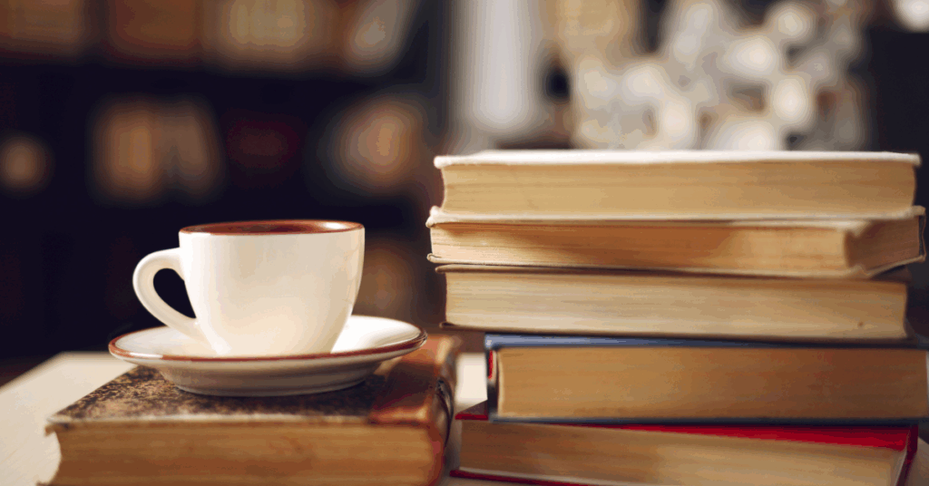 a pile of books, some looking old and a cup and saucer