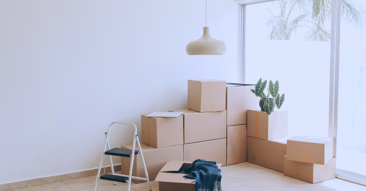 moving boxes piled up in the corner of a white living room