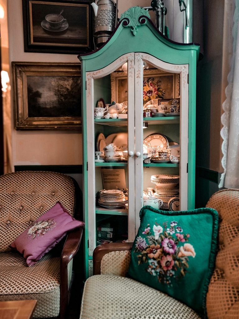 an upcycled corner unit that has been painted in green and white. Behind the glass is old crockery